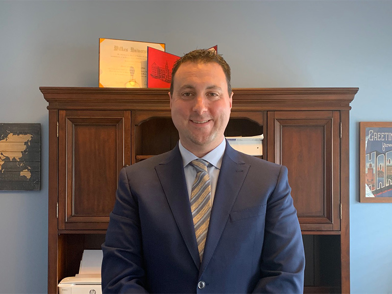 Joe Intrieri wearing suit and smiling in front of cabinet