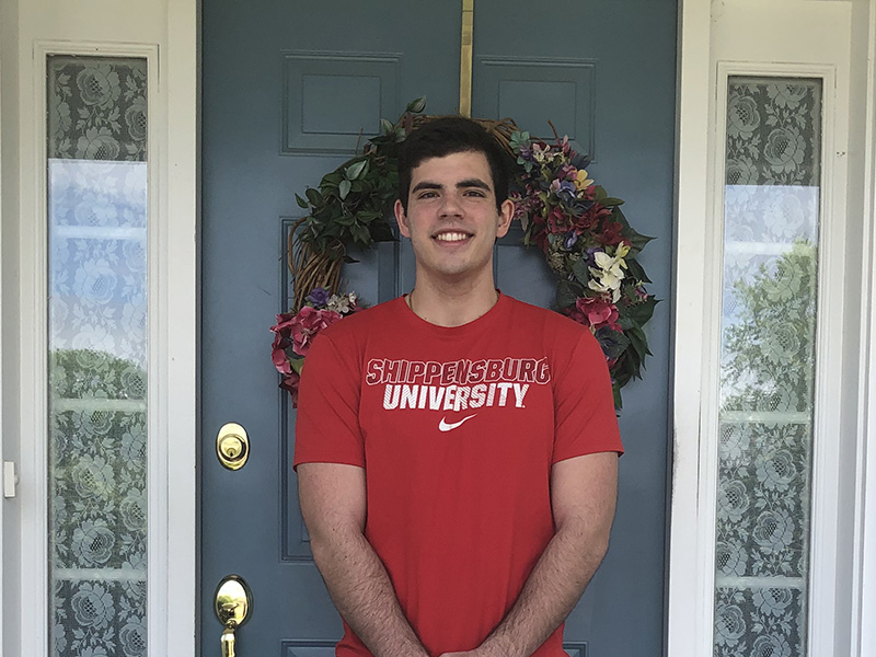 Bryan Rottkamp wearing Shippensburg University shirt and smiling in front of door
