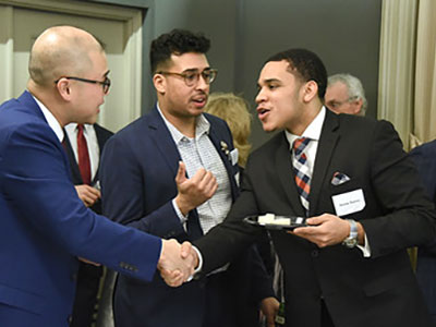 Alumni in suits greeting