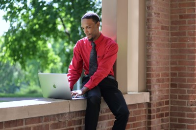 Male student works at laptop outside